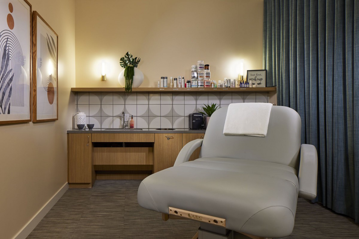 A serene spa treatment room featuring a comfortable massage chair and a well-organized countertop with various beauty and wellness products.