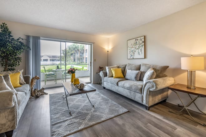 A modern living room with a cozy couch, stylish coffee table, and large sliding glass doors opening to a patio.