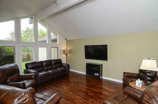 A cozy living room featuring modern brown leather sofas, a flat screen TV, and ample natural light from large windows.