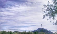 A scenic view of a mountain with a communication tower under a cloudy sky.