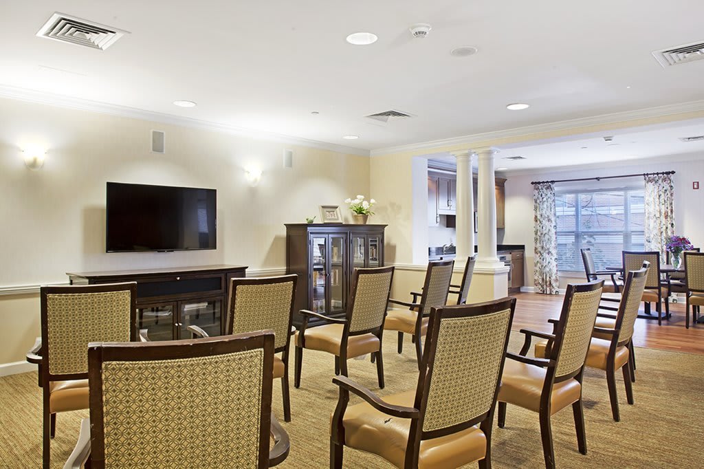 A well-arranged meeting room with chairs facing a television, creating a comfortable space for presentations or discussions.