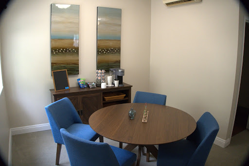 A modern meeting room featuring a round table surrounded by blue chairs and decorative artwork on the walls.