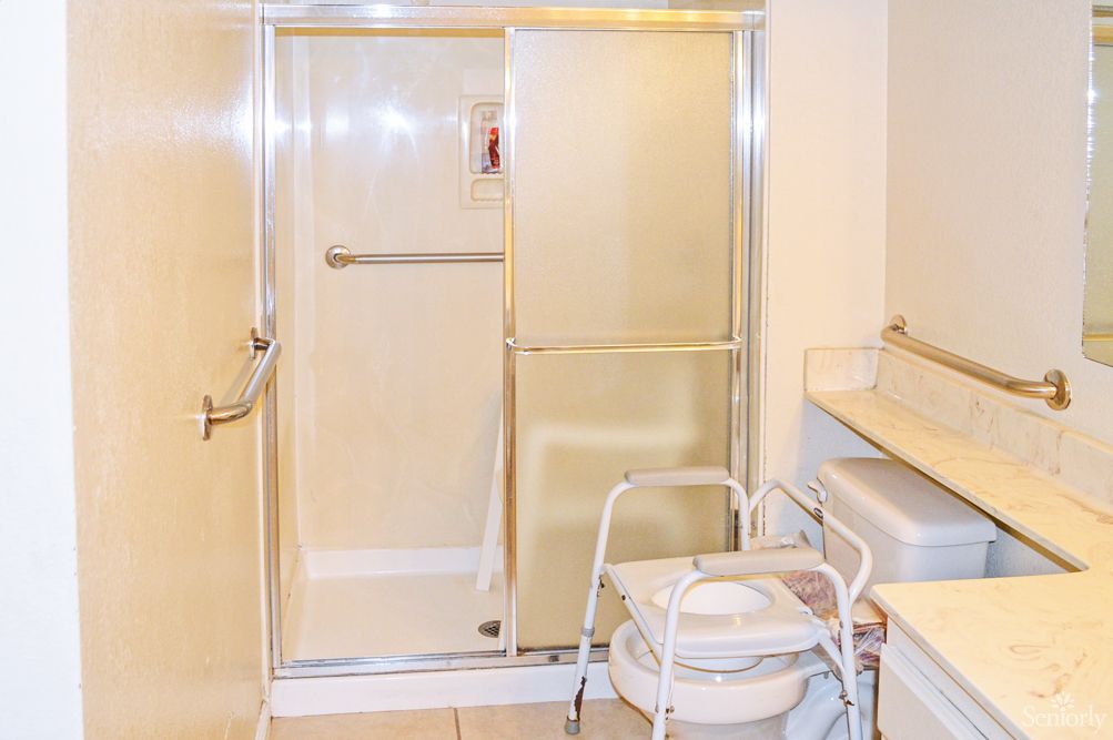 An accessible bathroom featuring a sliding door shower and a walker.
