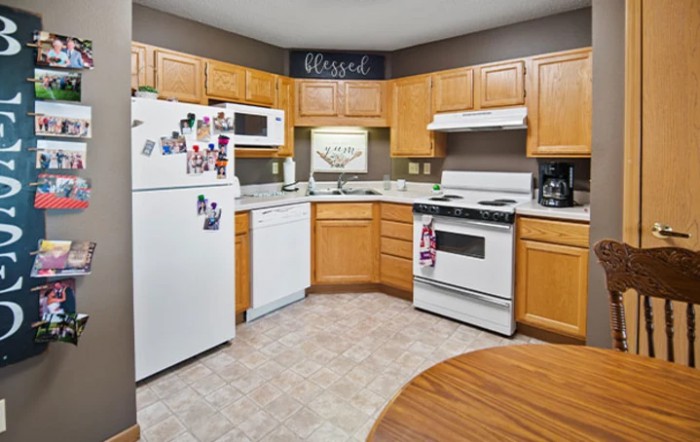 A cozy kitchen with wooden cabinets, featuring modern appliances like a refrigerator, stove, microwave, and dishwasher.