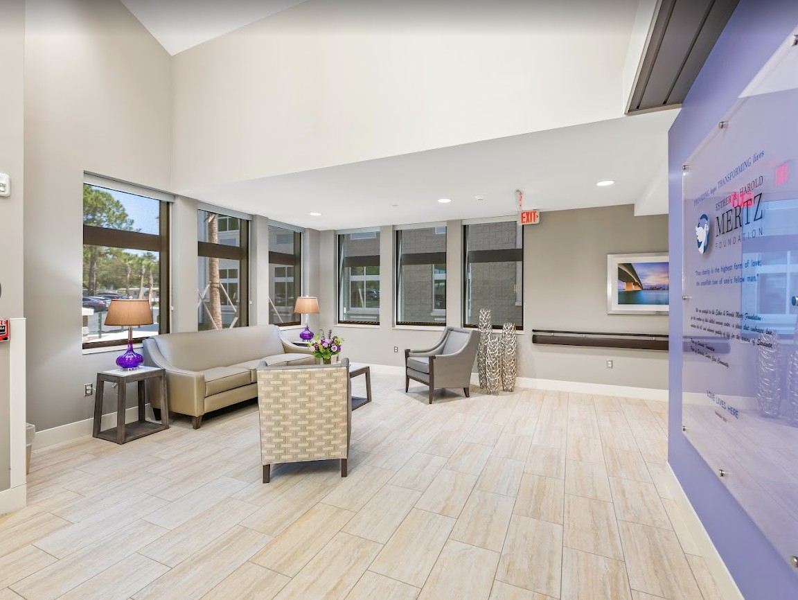 A modern living room with ample natural light streaming through large windows, featuring comfortable seating and stylish decor.