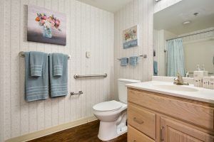 A neatly arranged bathroom with light wooden cabinetry, a toilet, and blue towels.