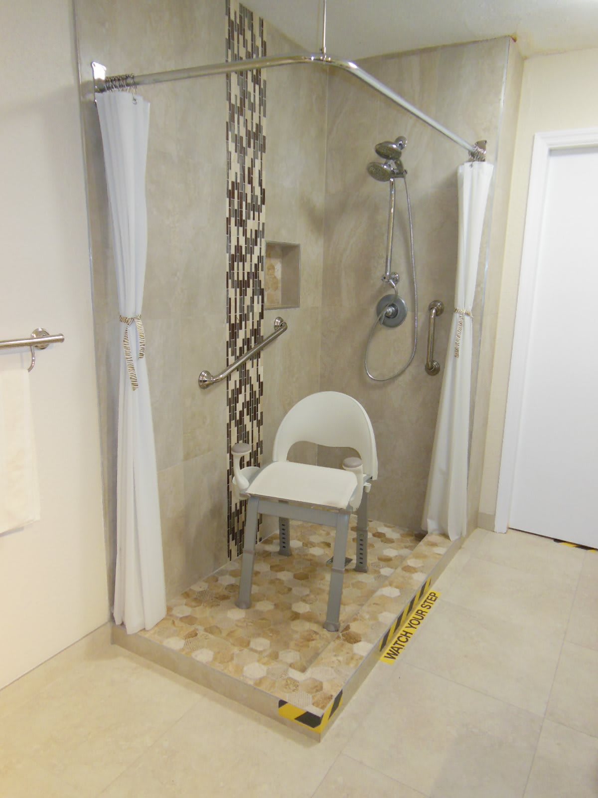 An accessible shower with a shower chair and safety grab bars.