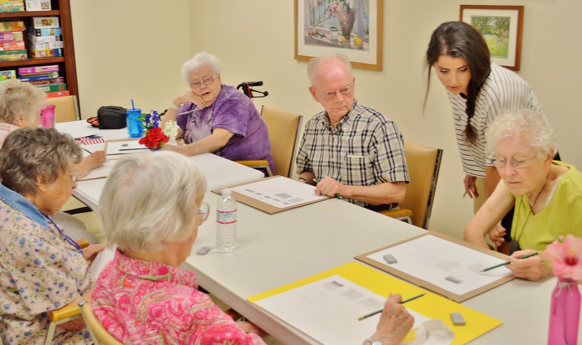 A group of seniors participates in an art class, each working on their own painting project.