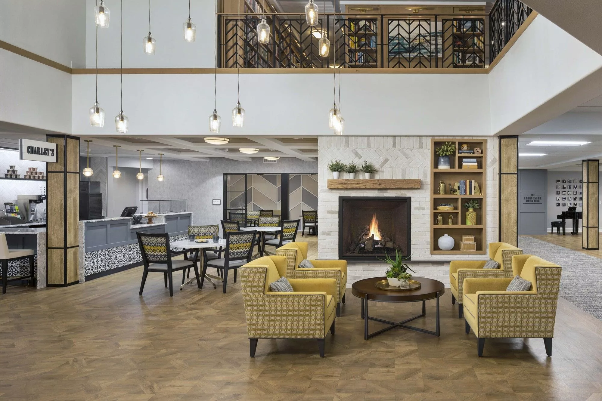 A modern hotel lobby with a cozy seating area featuring yellow chairs and a fireplace.