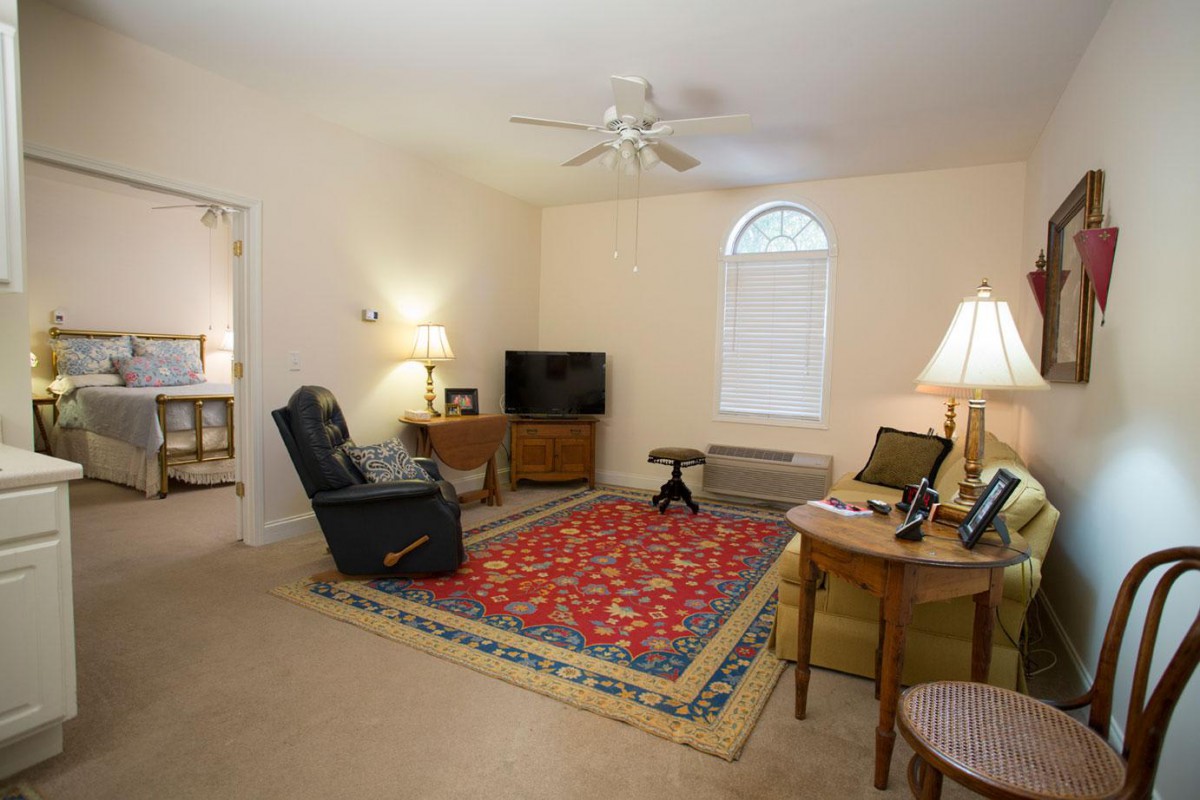 A cozy living room with a sofa, TV, and colorful rug.