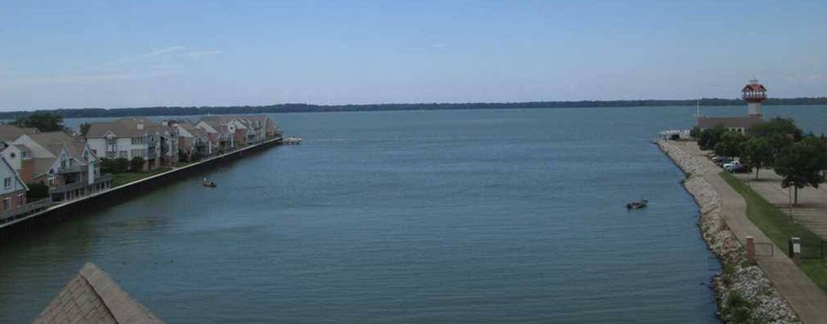 A peaceful view of a lake with a pier extending into the calm water under a clear blue sky.
