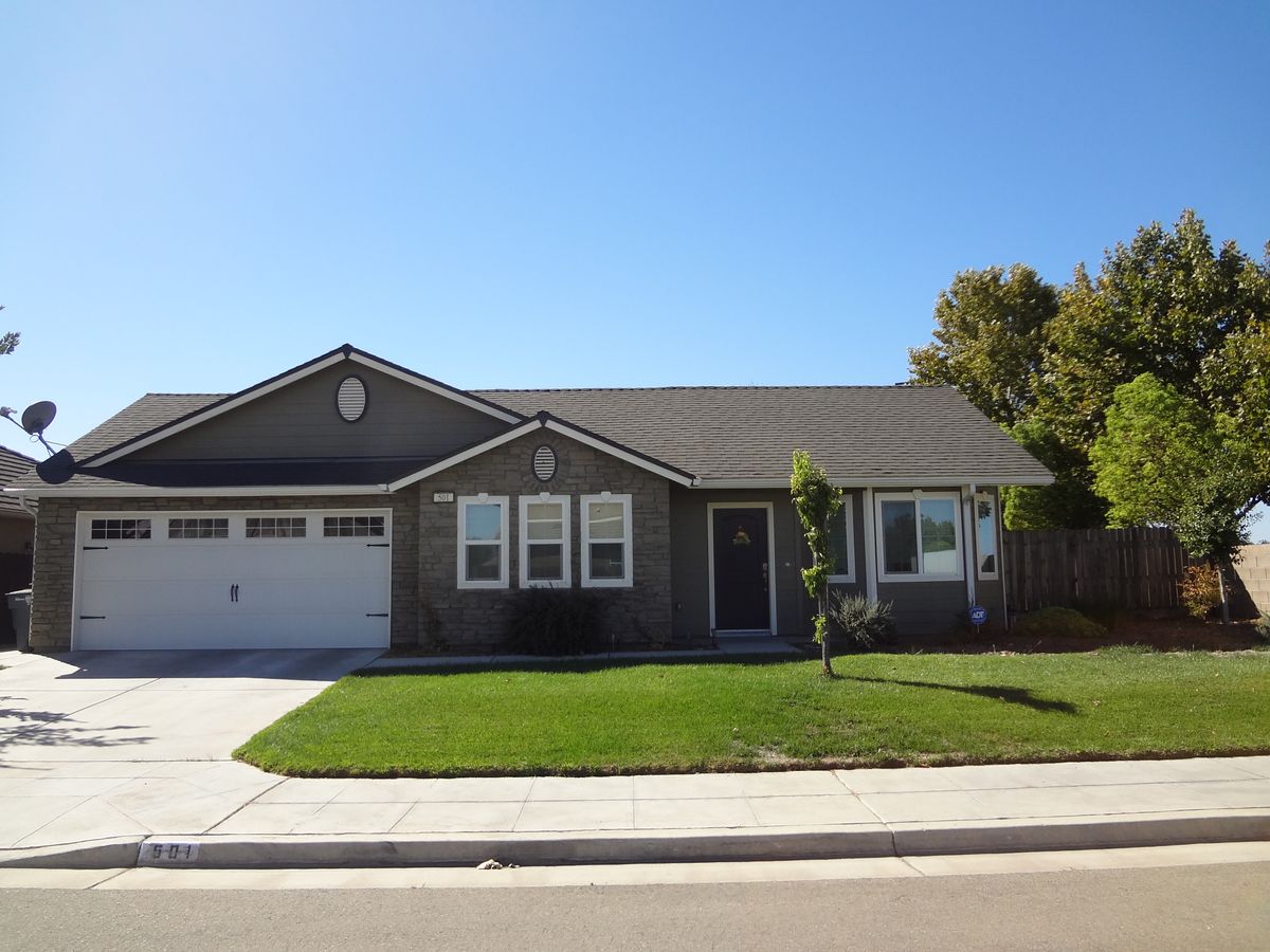 A single-story suburban house with a neatly maintained lawn and attached garage on a sunny day.