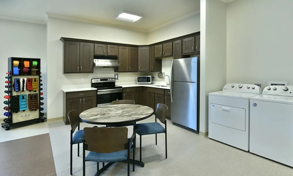 A modern kitchen and dining area with dark brown cabinets, stainless steel appliances, and a round table with chairs.