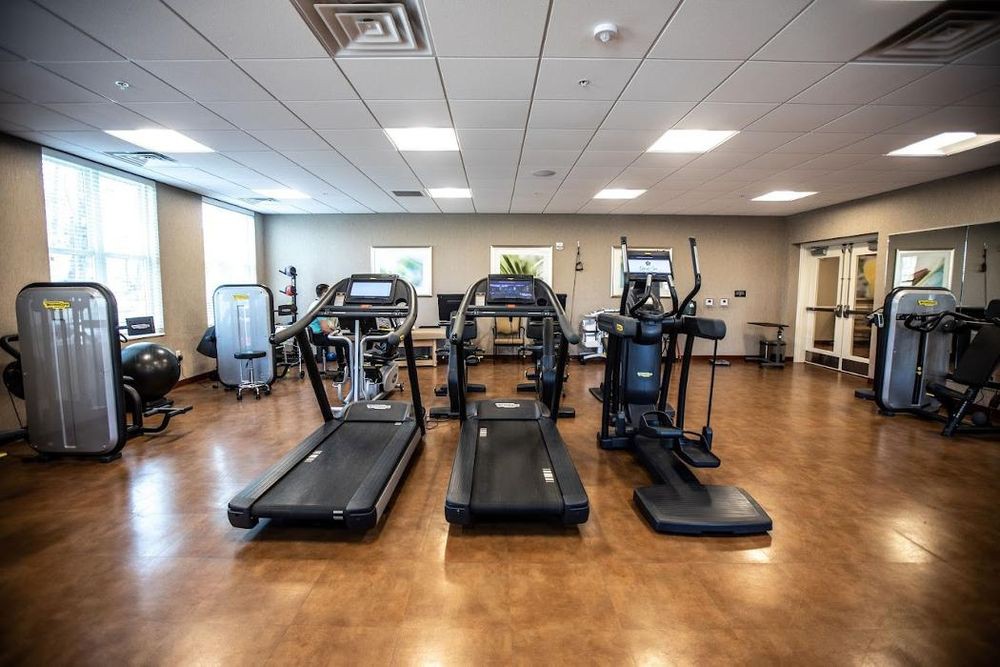A spacious gym room with treadmills and an elliptical machine lined up for a workout.