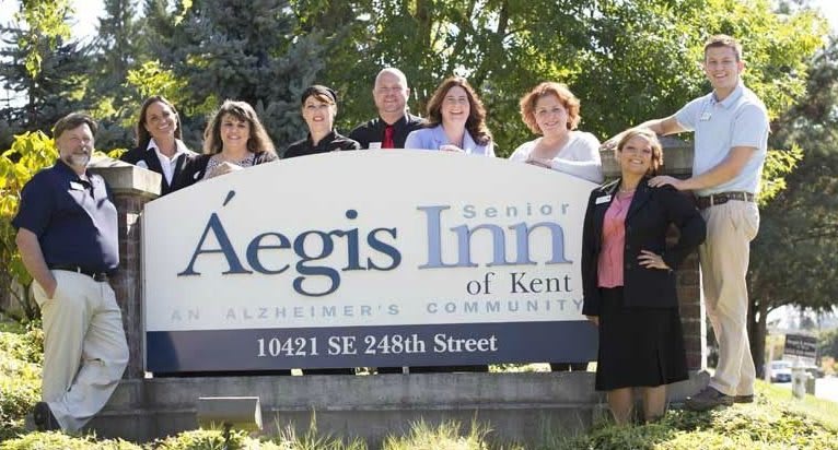 A group of people standing in front of the Aegis Inn of Kent sign.