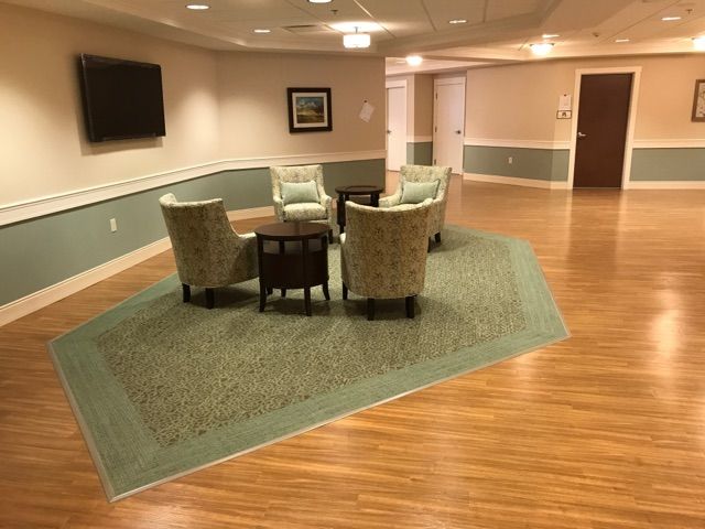 A cozy seating area with four chairs around a table on a carpeted section of the floor in a hallway.