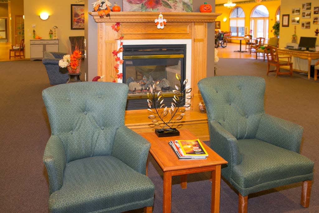 A cozy living room with two armchairs, a small table, and a fireplace.