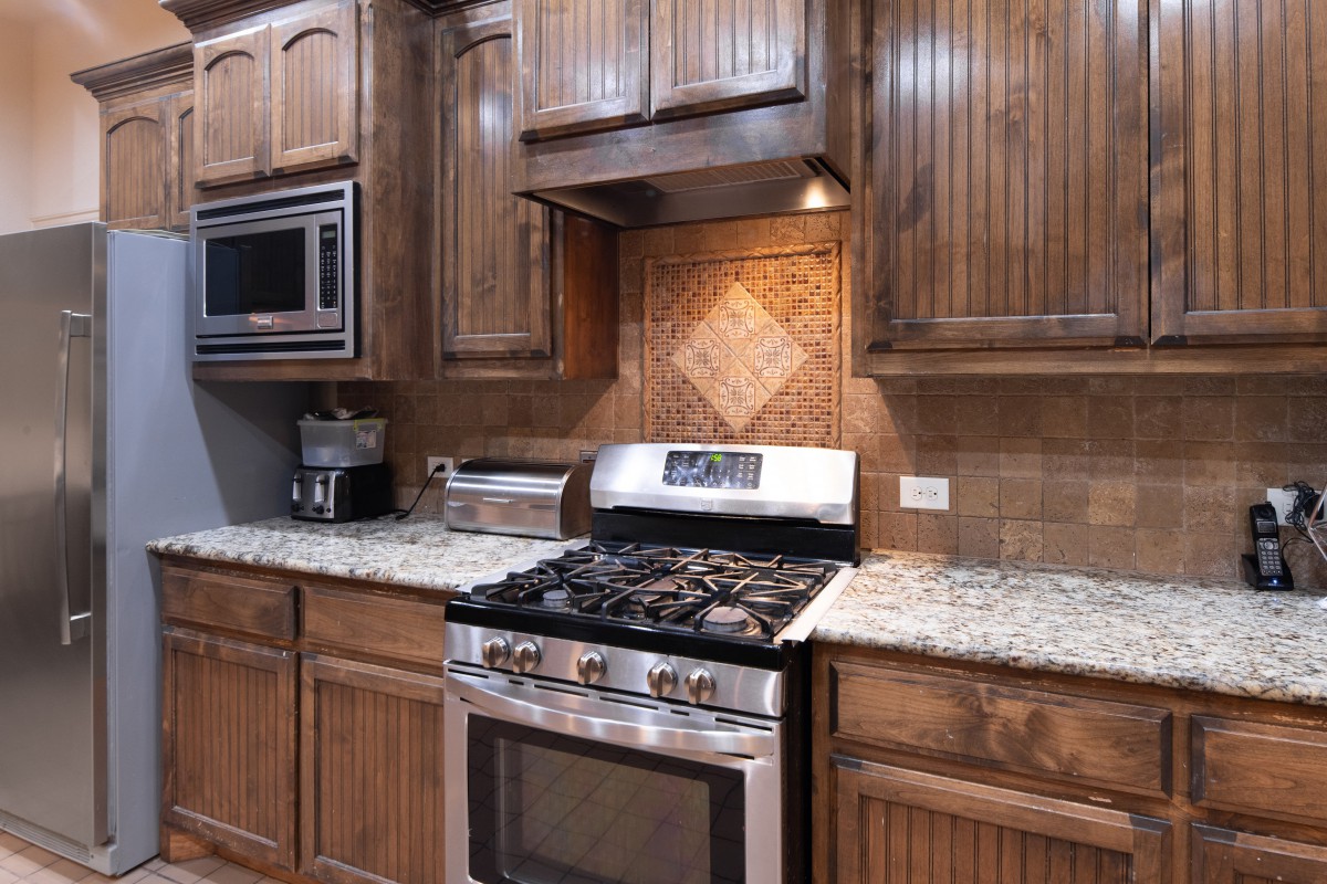 A modern kitchen with wooden cabinets, a granite countertop, and stainless steel appliances.