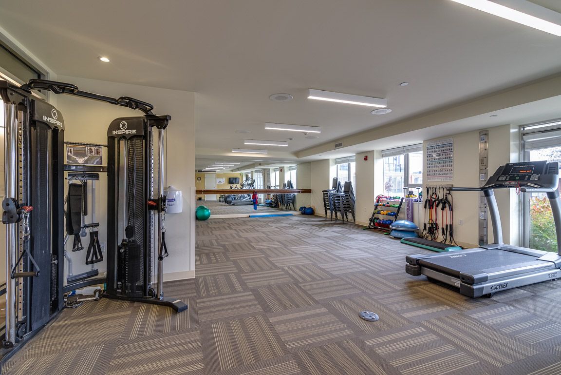 A spacious gym with various exercise equipment and a large mirror.