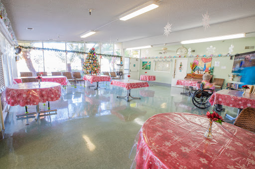 A spacious community center decorated for the holiday season, featuring tables with red covers and a Christmas tree.