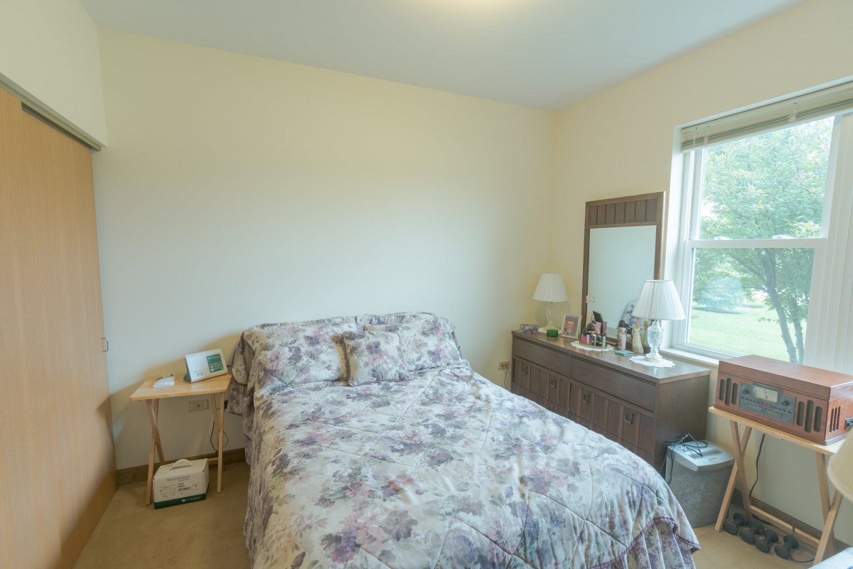 A cozy bedroom with floral bedding and a dresser beside a window.
