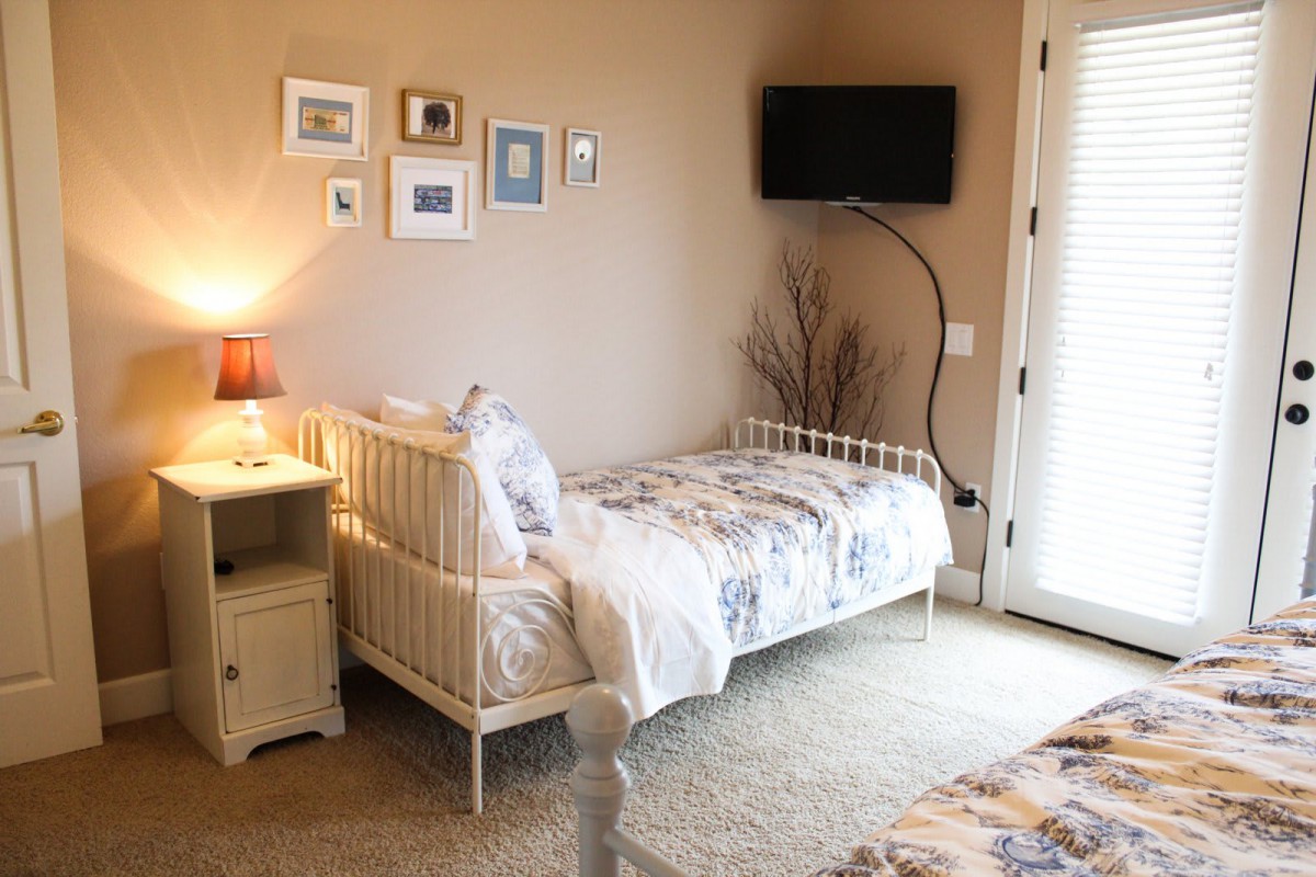 A cozy bedroom with a single bed, wall art, and a TV mounted on the wall.