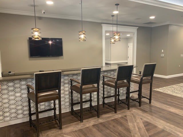 A modern bar area with high chairs, a counter, and a mounted television.