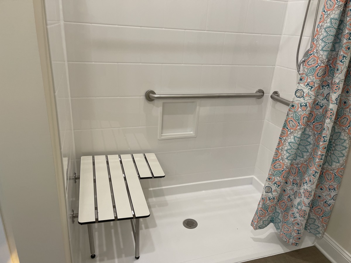 Accessible shower with a bench and grab bars.