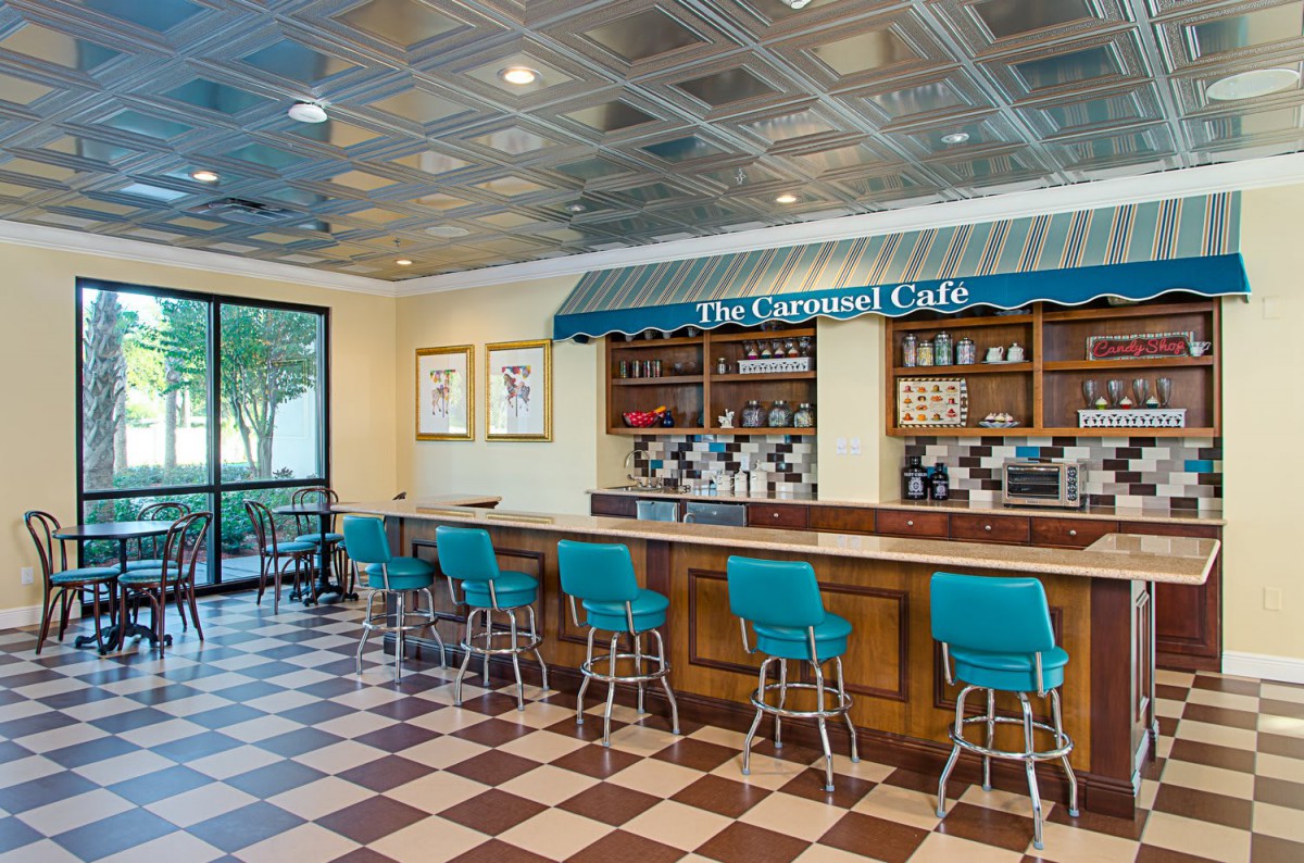 Retro-style cafe interior with a checkered floor and blue barstools at the counter.