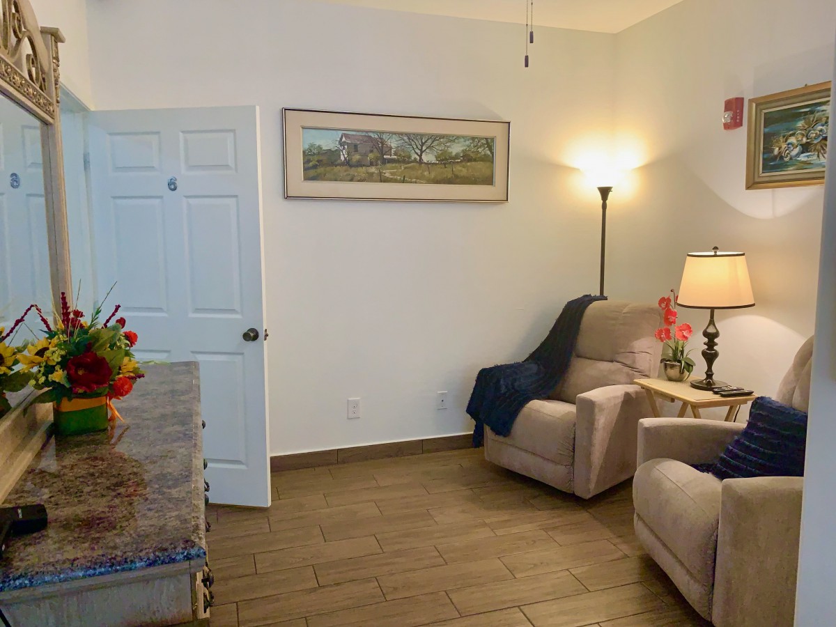 A cozy living room with armchairs, a lamp, and wall decor.