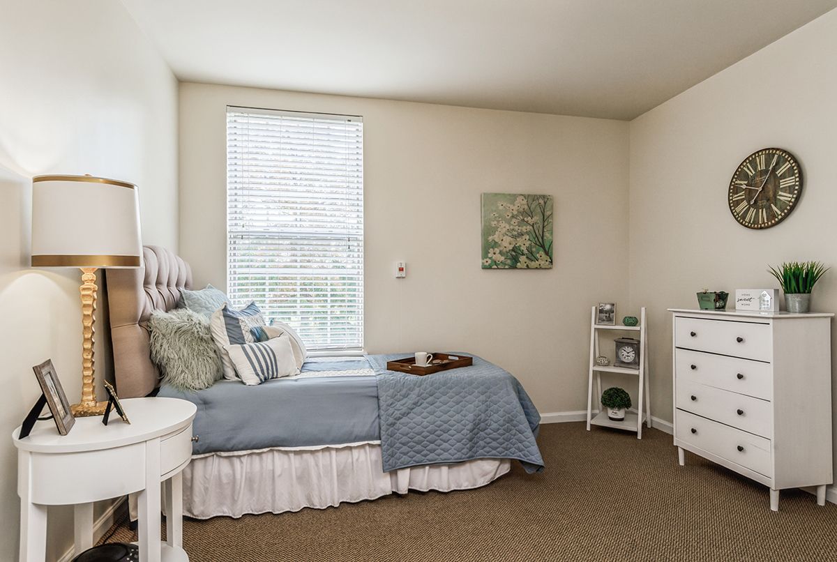 A cozy and well-decorated bedroom featuring blue bedding, white walls, and stylish furnishings.