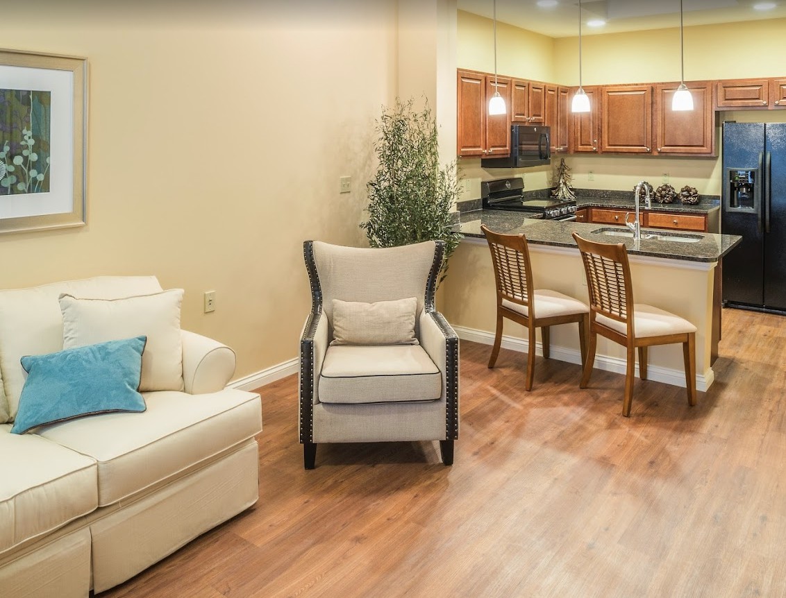 A cozy open-concept living room and kitchen with modern furnishings and warm hardwood floors.