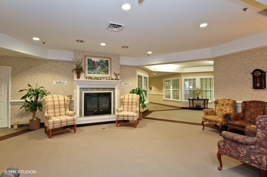 A cozy living room with a fireplace, armchairs, and decorative elements.