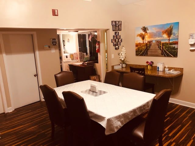 A cozy dining room setup with a table, surrounded by chairs and decorated with artwork on the wall.