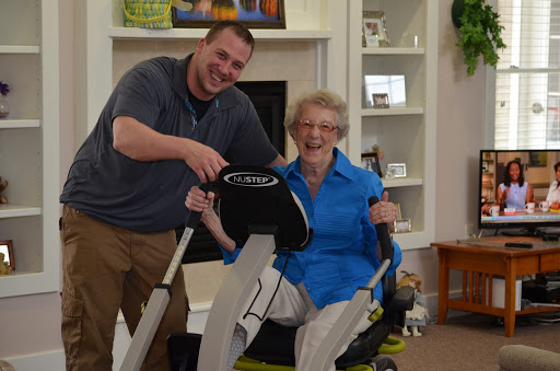 A joyful moment shared between a man and an elderly woman as they enjoy using exercise equipment together.