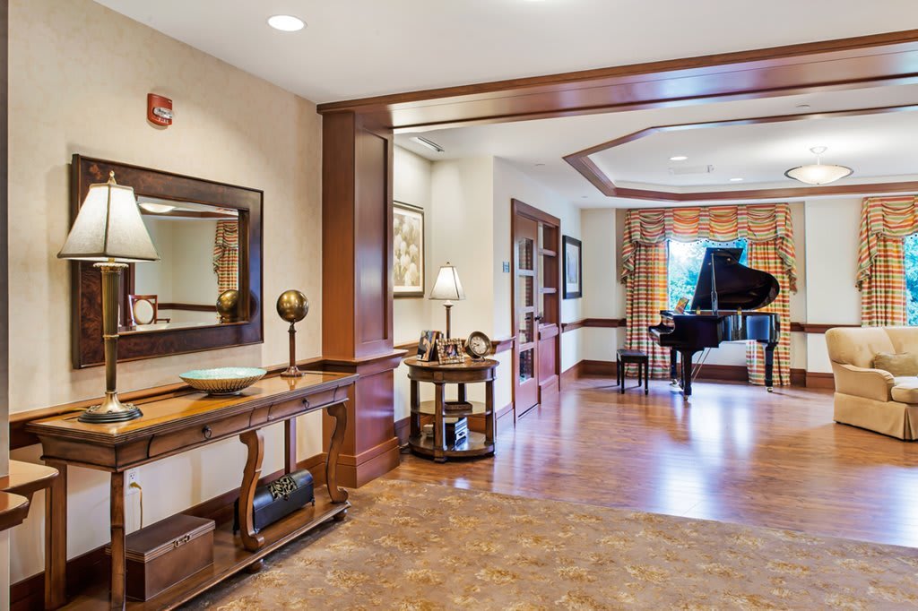 A spacious living room with a grand piano and elegant decor.