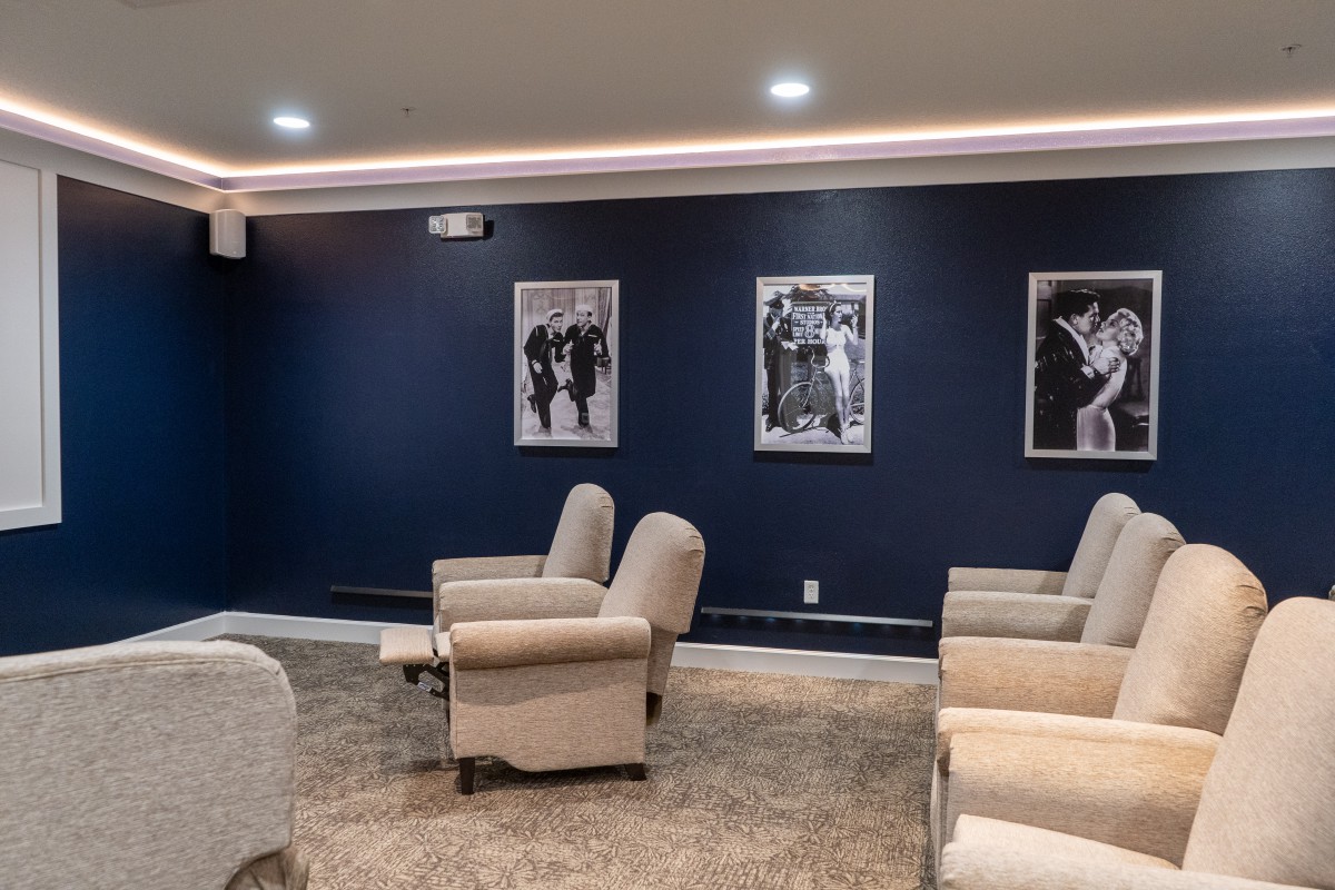 A modern lounge area with comfortable seating and black-and-white photos on a dark blue wall.