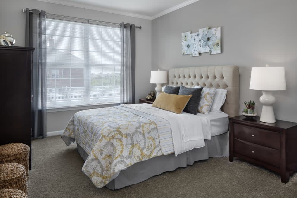 A cozy and well-decorated bedroom with a large bed, bedside table, and natural light from a window.