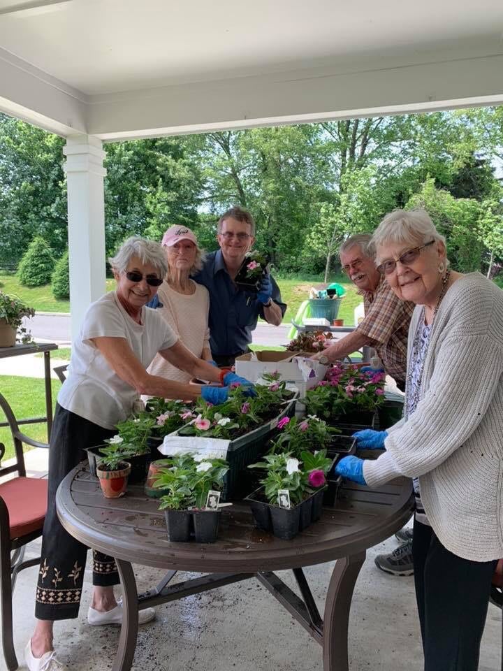 A group of older adults enjoying gardening together outdoors at a table.