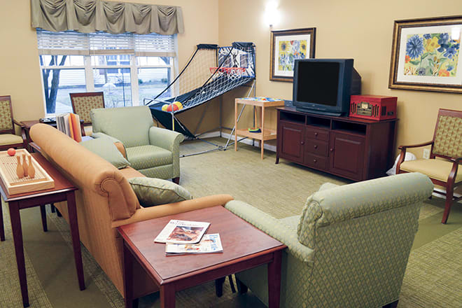 A cozy living room with seating, a television, and an arcade basketball game.