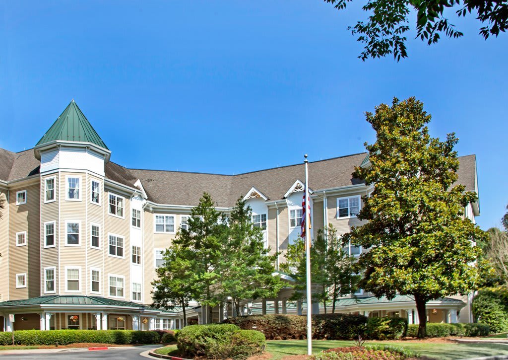 A multi-story building surrounded by trees under a clear blue sky.