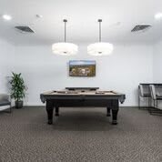 A modern game room featuring a pool table with stylish lighting.