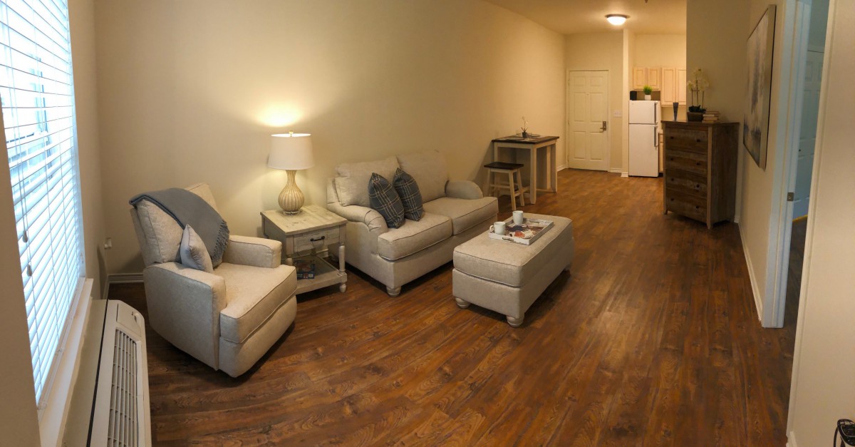 A cozy living room with a sofa, armchair, and warm lighting.