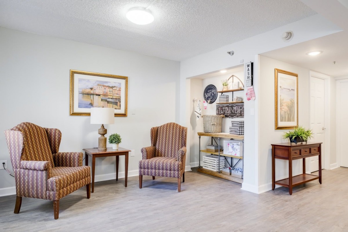 A cozy lobby area featuring striped armchairs, artwork on the walls, and a small table with decorative items.