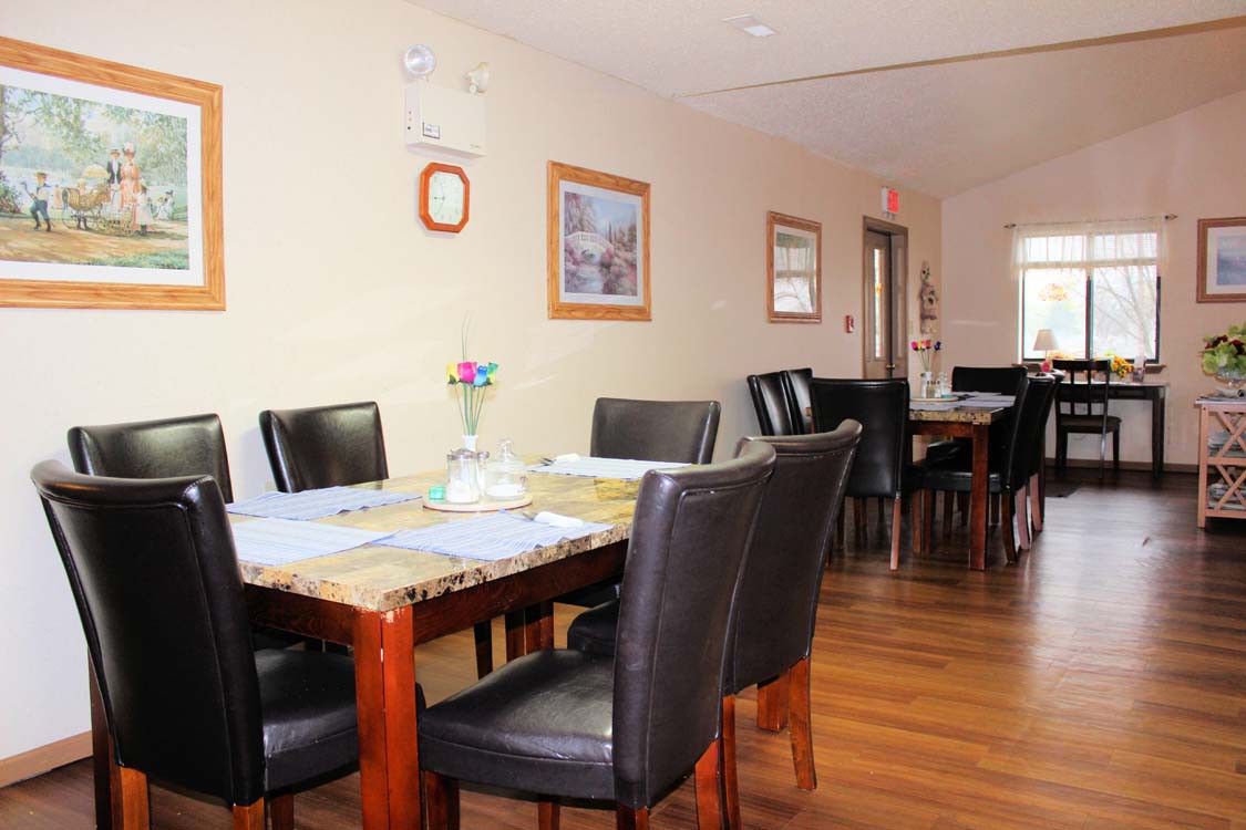 A neatly arranged dining room with wooden tables and black chairs, featuring decorative elements on the walls.