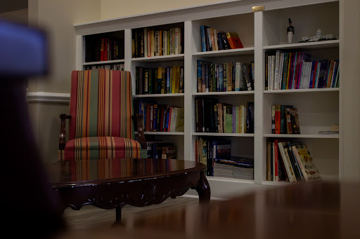 A cozy reading corner featuring a striped chair and shelves filled with books.