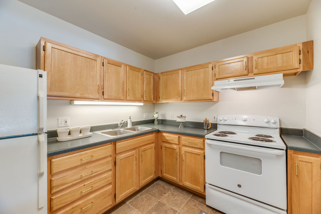 A kitchen with wooden cabinets, a white stove, and sink.