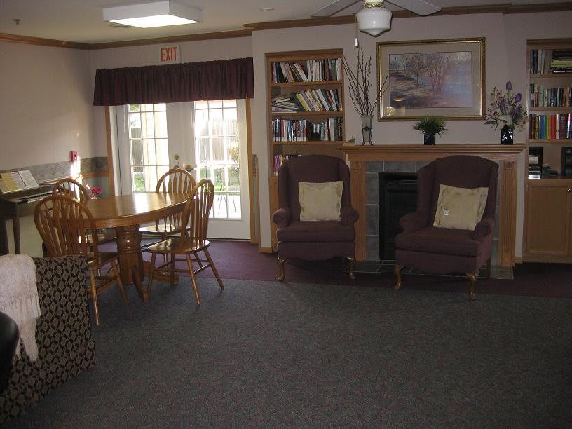 A cozy living room featuring a dining table, bookshelf, and fireplace.