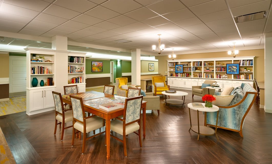 A cozy lounge area with bookshelves, comfortable seating, and a table and chairs.