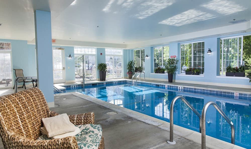 A luxurious indoor swimming pool with elegant furniture and natural lighting.